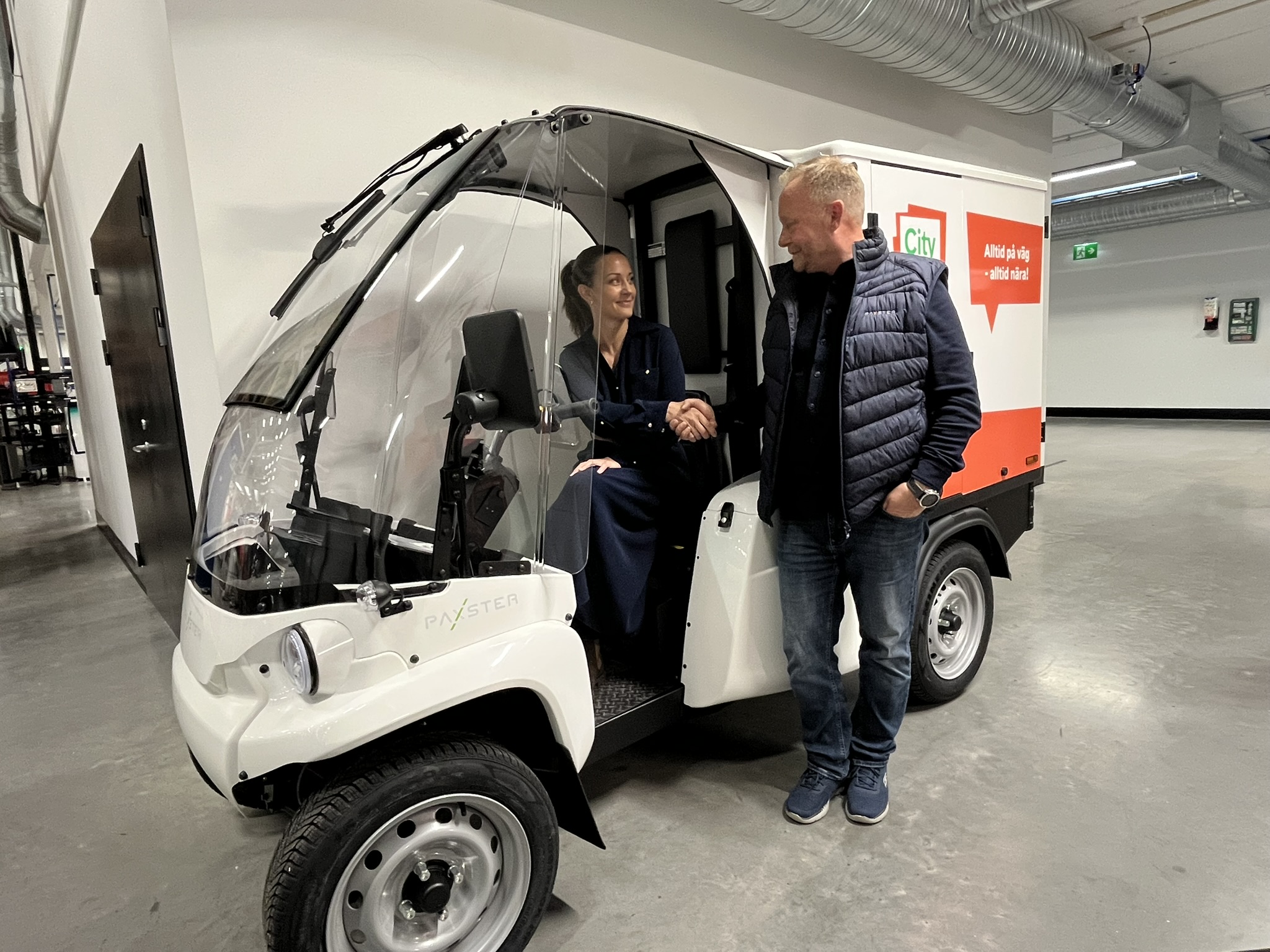 To personer håndhilser ved et elektrisk Paxster-kjøretøy som symbol på nytt samarbeid mellom Brage Finans og Paxster.